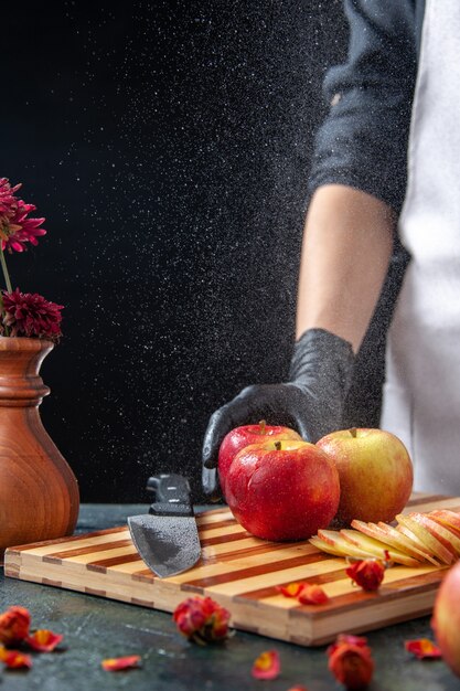 Vooraanzicht vrouwelijke kok die appels snijdt op een donkere fruitdieetsalade voedselmaaltijd exotisch sapwerk