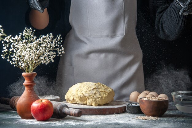 Vooraanzicht vrouwelijke kok die deeg uitrolt met bloem op donkere baan deeg gebak hotcake keuken bakkerij ei keuken