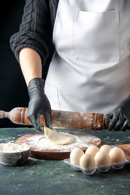 Vooraanzicht vrouwelijke kok die deeg uitrolt met bloem op donkere cake baan oven hotcake bak taart werknemer ei keuken deeg