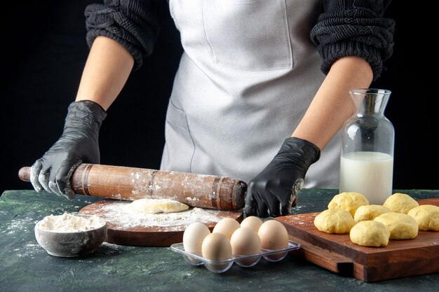 Vooraanzicht vrouwelijke kok die deeg uitrolt met bloem op donkere cake baan oven hotcake deeg taart werknemer ei keuken