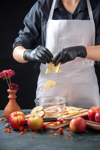 Gratis foto vooraanzicht vrouwelijke kok die gesneden appels in plaat zet op donkere fruitdieetsalade voedselmaaltijd exotisch sapwerk