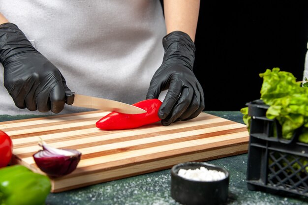 Vooraanzicht vrouwelijke kok die rode peper snijdt op grijs voedsel koken salade keuken keuken maaltijd