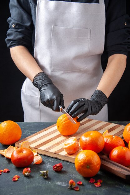 Vooraanzicht vrouwelijke kok die sinaasappel op een grijze salade snijdt gezondheid maaltijd voedsel baan groente vers drankje fruit dieet