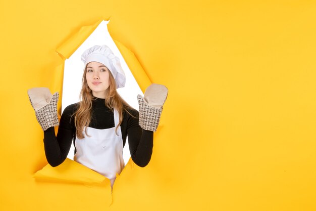 Vooraanzicht vrouwelijke kok in kokshandschoenen en witte koksmuts op een gele zon voedselkleur keuken foto emotie keuken baan