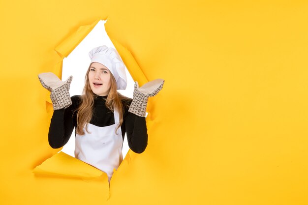 Vooraanzicht vrouwelijke kok in kokshandschoenen en witte koksmuts op gele zon voedselkleur keuken emotie keuken baan