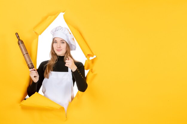 Vooraanzicht vrouwelijke kok met deegroller op gele zon kleur keuken baan keuken foto emotie