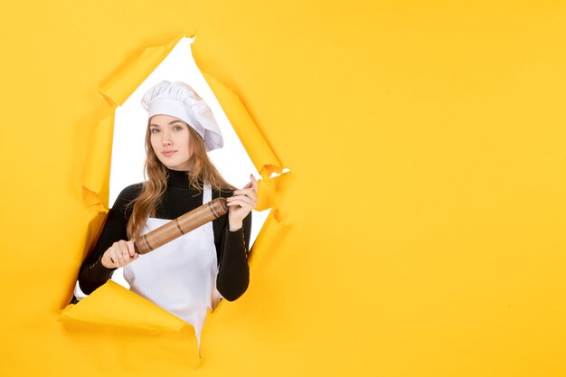 Vooraanzicht vrouwelijke kok met deegroller op gele zon voedselkleur baan keuken foto emotie keuken