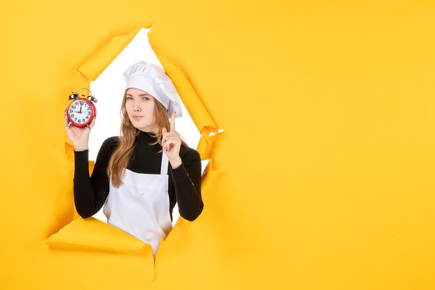 Vooraanzicht vrouwelijke kok met klokken op geel voedsel foto kleur baan keuken keuken emotie zon