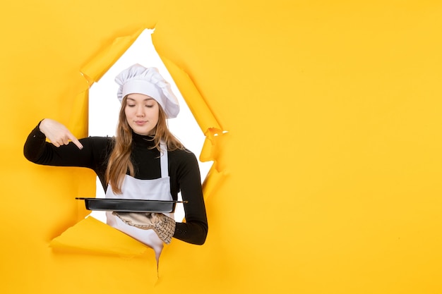 Vooraanzicht vrouwelijke kok met zwarte pan op gele emotie zon voedsel foto baan keuken keuken