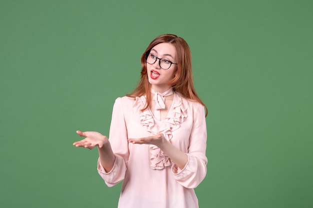 Vooraanzicht vrouwelijke leraar in roze blouse op groene achtergrond boek studenten baan school college kleur werk bibliotheek vrouw jonge les