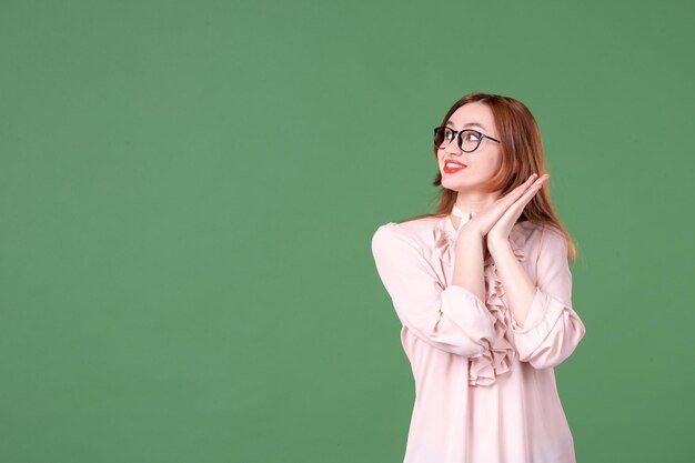 Vooraanzicht vrouwelijke leraar in roze blouse op groene achtergrond school kleur bibliotheek college baan vrouw student jong boek les