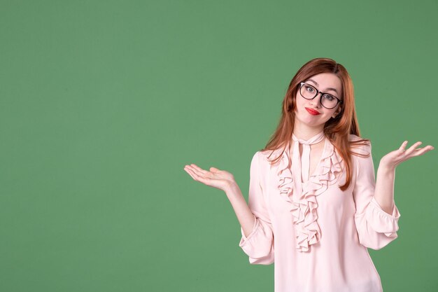 Vooraanzicht vrouwelijke leraar in roze blouse poseren op groen