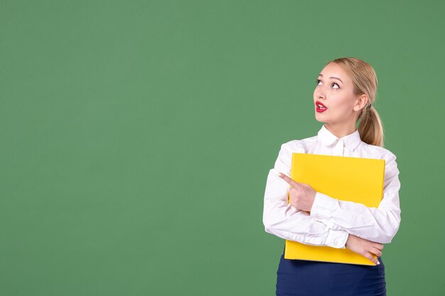 Vooraanzicht vrouwelijke leraar met gele bestanden op groene achtergrond boek studie uniform les student school werk universiteit vrouw