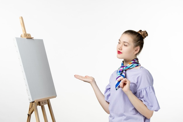 Vooraanzicht vrouwelijke schilder met ezel voor het schilderen op witte muur kunst foto kunstenaar verf trek foto kwastje