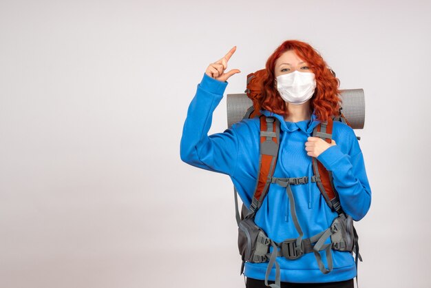 Vooraanzicht vrouwelijke toerist die in bergreis in masker met rugzak gaat