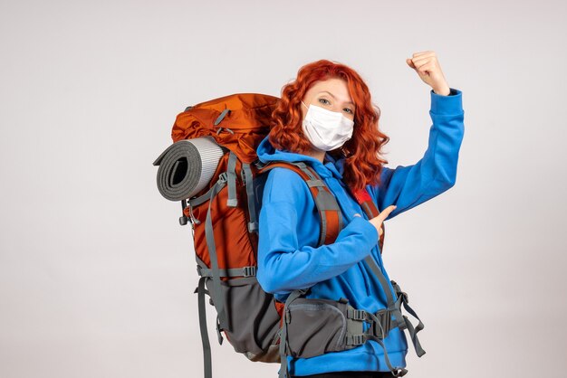 Vooraanzicht vrouwelijke toerist die in bergreis in masker met rugzak gaat