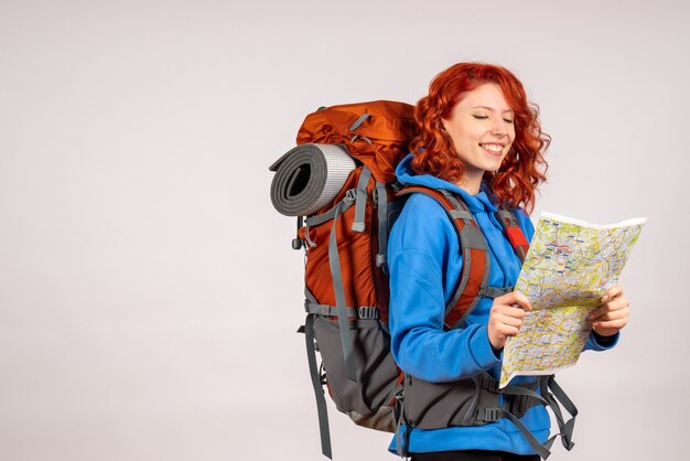 Vooraanzicht vrouwelijke toerist die in bergreis met rugzak en kaart gaat