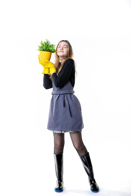 Vooraanzicht vrouwelijke tuinman in gele handschoenen met kleine plant op wit