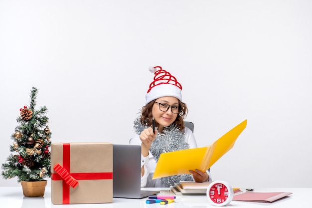 Vooraanzicht vrouwelijke werknemer die voor haar plaats zit en werkt met documenten kantoor zakelijke kerstbaan