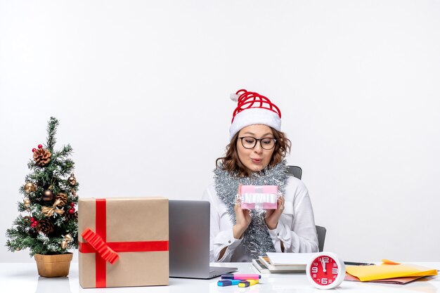 Vooraanzicht vrouwelijke werknemer die voor haar werkplek zit en een klein cadeautje vasthoudt