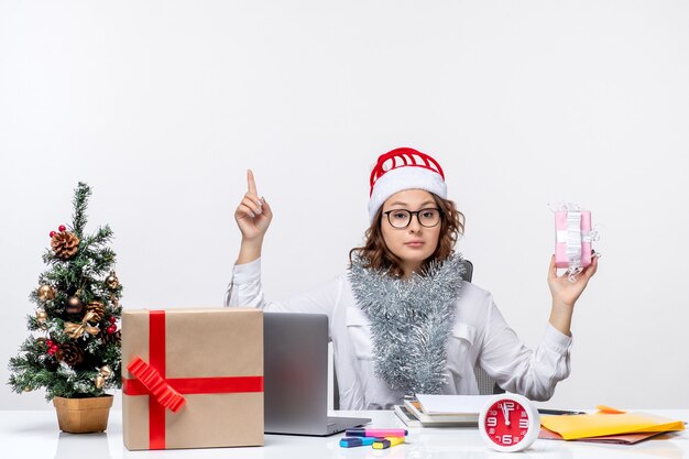 Vooraanzicht vrouwelijke werknemer die voor haar werkplek zit en een klein cadeautje vasthoudt