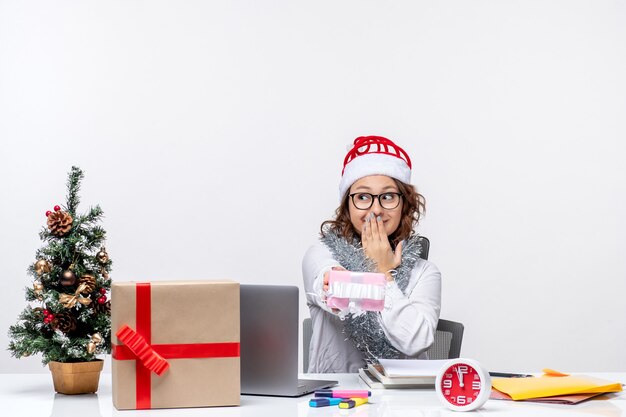 Vooraanzicht vrouwelijke werknemer die voor haar werkplek zit met een klein aanwezig vrouwwerk kerstkantoor