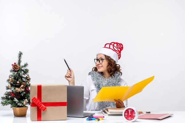 Vooraanzicht vrouwelijke werknemer zit voor haar plaats en werkt met documenten kantoor werk baan zakelijke kerst