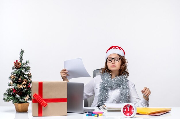 Vooraanzicht vrouwelijke werknemer zit voor haar werkplek met laptop en bestanden baan emotie business office xmas