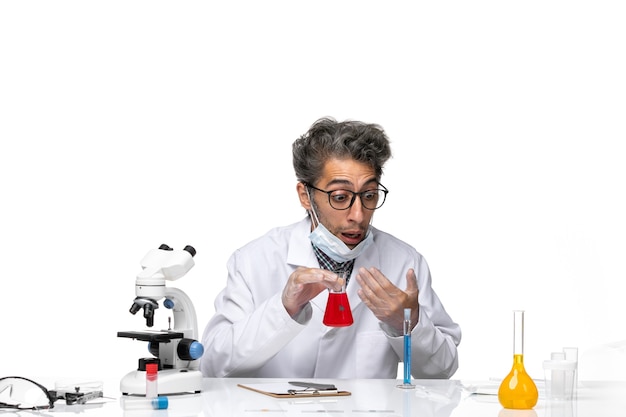 Vooraanzicht wetenschapper van middelbare leeftijd in speciale witte pak ruikende oplossing