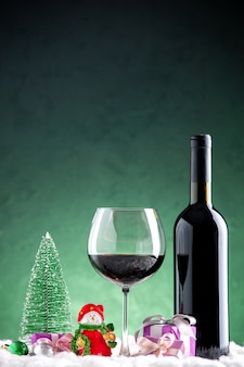 Vooraanzicht wijnglas en fles kerst ornamenten op groene achtergrond