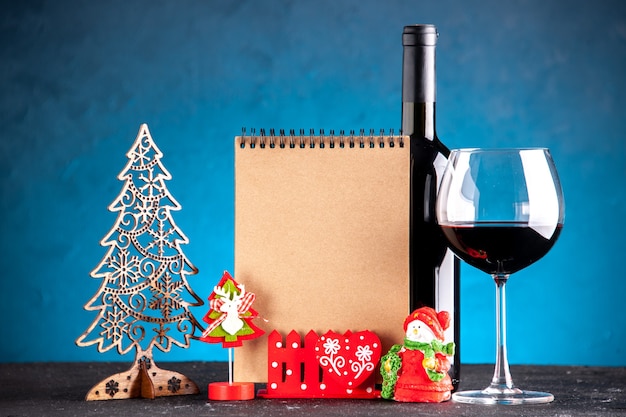 Vooraanzicht wijnglas en fles kerstdecoratie notitieboekje op lichtblauwe achtergrond