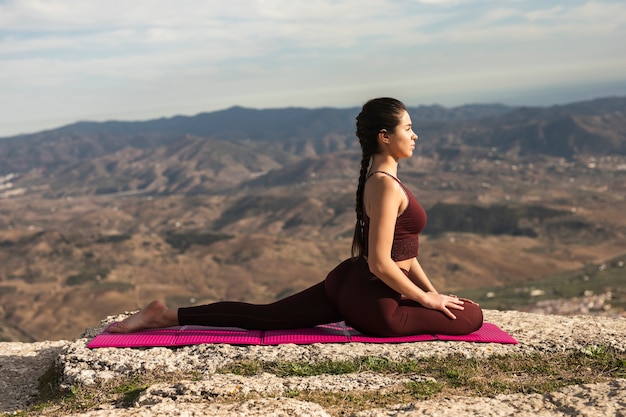 Gratis foto vooraanzicht yoga pose op mat met jonge vrouw