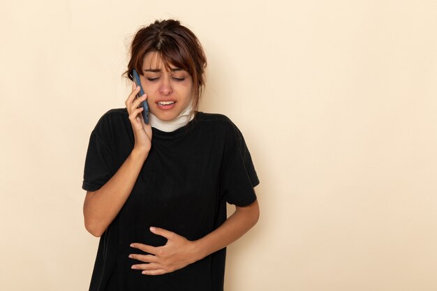 Vooraanzicht zieke jonge vrouw erg ziek voelen en praten aan de telefoon op wit bureau