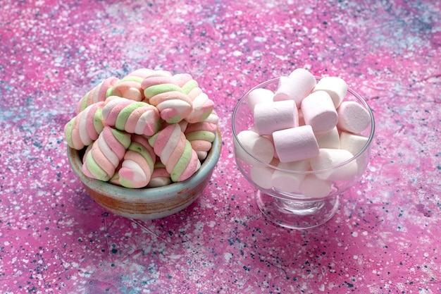 Gratis foto vooraanzicht zoete gekleurde marshmallows gevormd in ronde pot met witte op roze bureau.