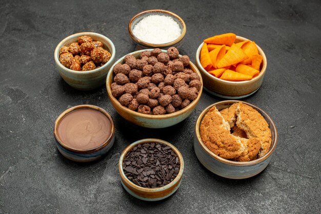 Vooraanzicht zoete noten met cacaovlokken en cips op donkere achtergrond snack melk maaltijd ontbijt kleur