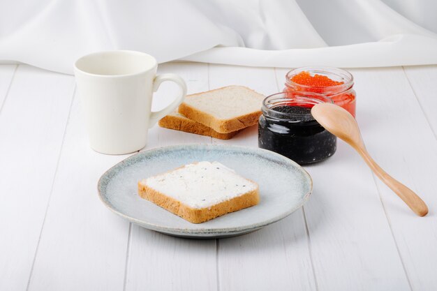 Vooraanzicht zwarte en rode kaviaar met toast met boter op een bord met een kopje koffie