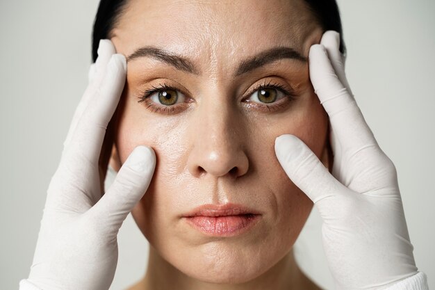 Vooraanzichthanden met handschoenen die het gezicht van de vrouw aanraken