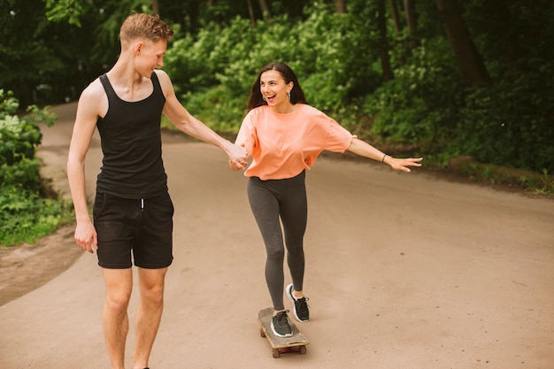 Gratis foto vooraanzichtjongen die meisje met een skateboard rijden