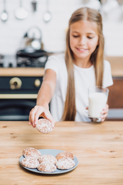 Gratis foto vooraanzichtmeisje die een koekje van een plaat nemen