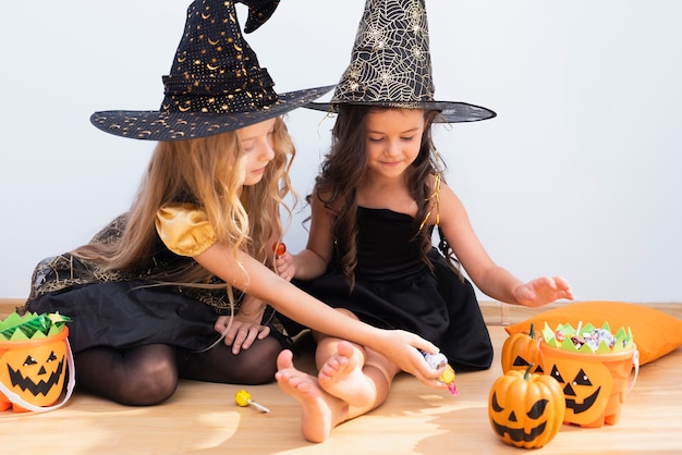 Gratis foto vooraanzichtmeisjes die op vloer op halloween zitten