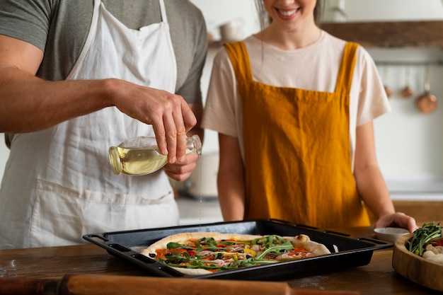 Vooraanzichtmensen die pizza in keuken koken