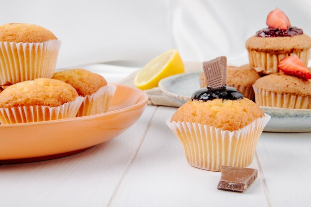 Vooraanzichtmuffins met chocolade en aardbeien op een plaat met citroen