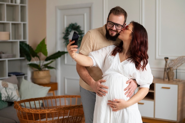 Vooraanzichtpaar dat zwangerschap met smartphone aankondigt