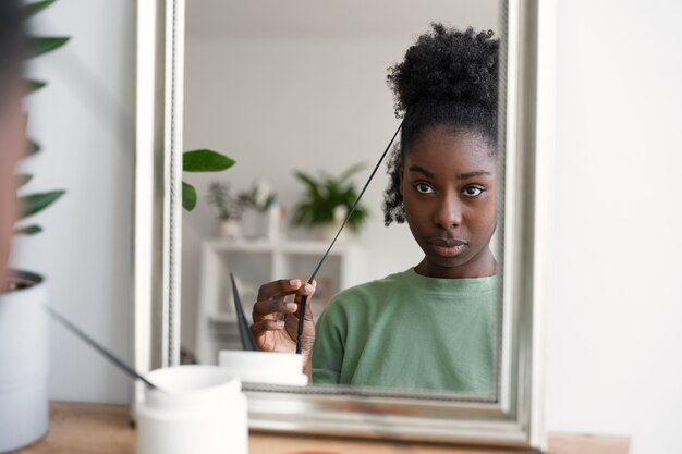 Vooraanzichtvrouw die haar in spiegel schikt