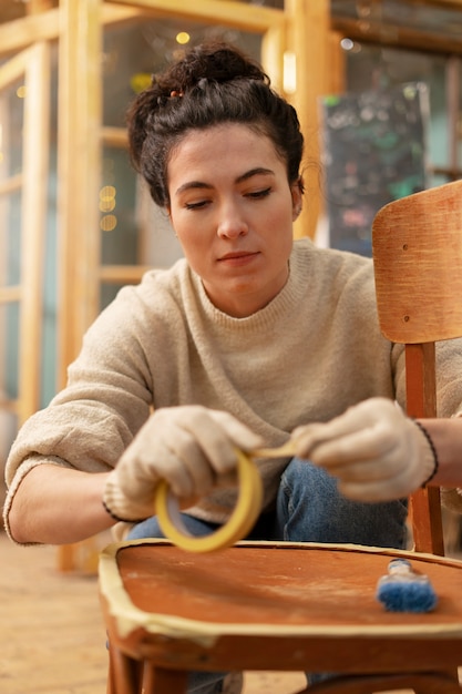 Gratis foto vooraanzichtvrouw die houten meubilair herstelt