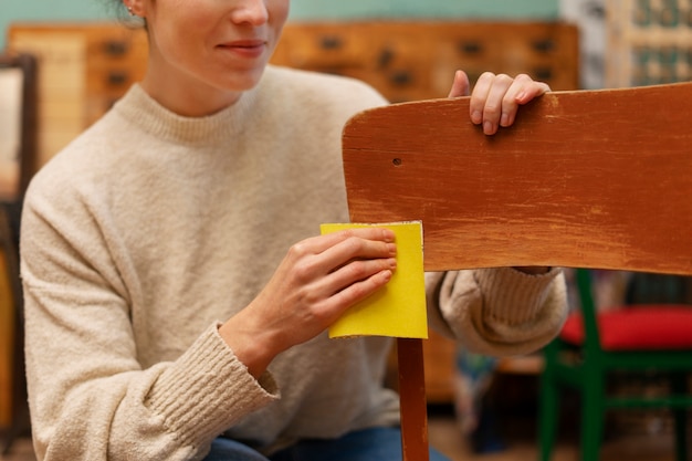 Gratis foto vooraanzichtvrouw die houten stoel herstelt