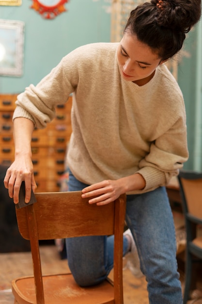 Vooraanzichtvrouw die houten stoel herstelt