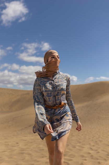 Vooraanzichtvrouw die sjaal in woestijn draagt