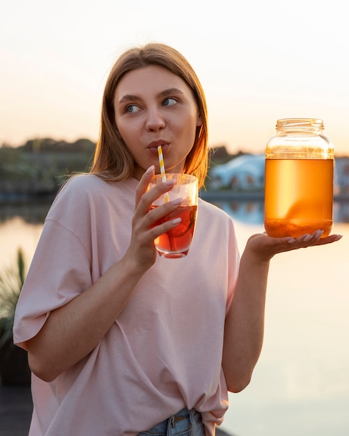 Gratis foto vooraanzichtvrouw met heerlijke kombucha in openlucht