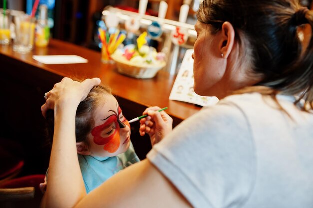 Voorbereiden op Pasen-concept Vrouw die aqua-make-up doet voor babymeisje